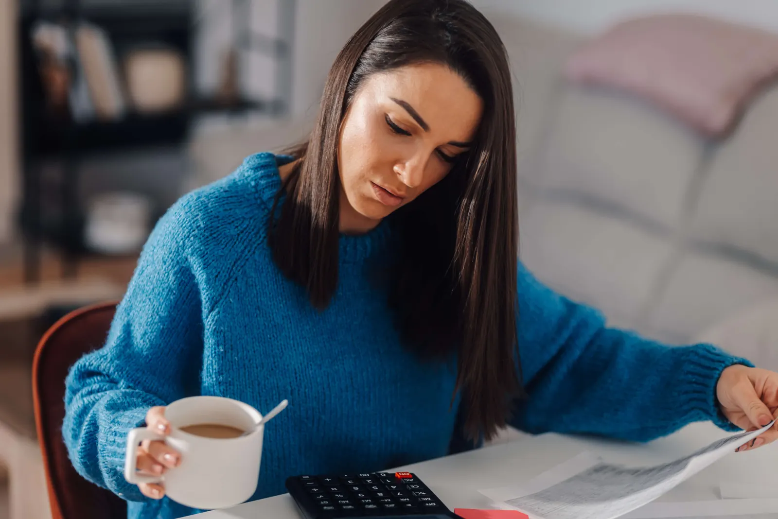 A woman working through bills at her kitchen table